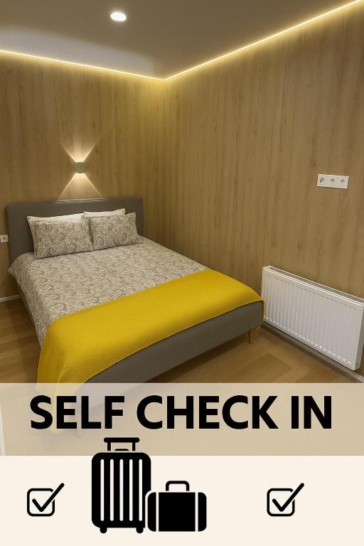 a bedroom with a bed with yellow sheets and two suitcases at 15 New Airport Apartment in Vilnius