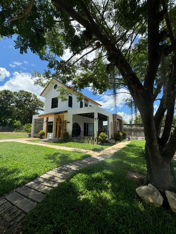 a white house with a tree in the foreground at Eden Villa - Verdant Garden, Mountain View Villa in Pai in Pai