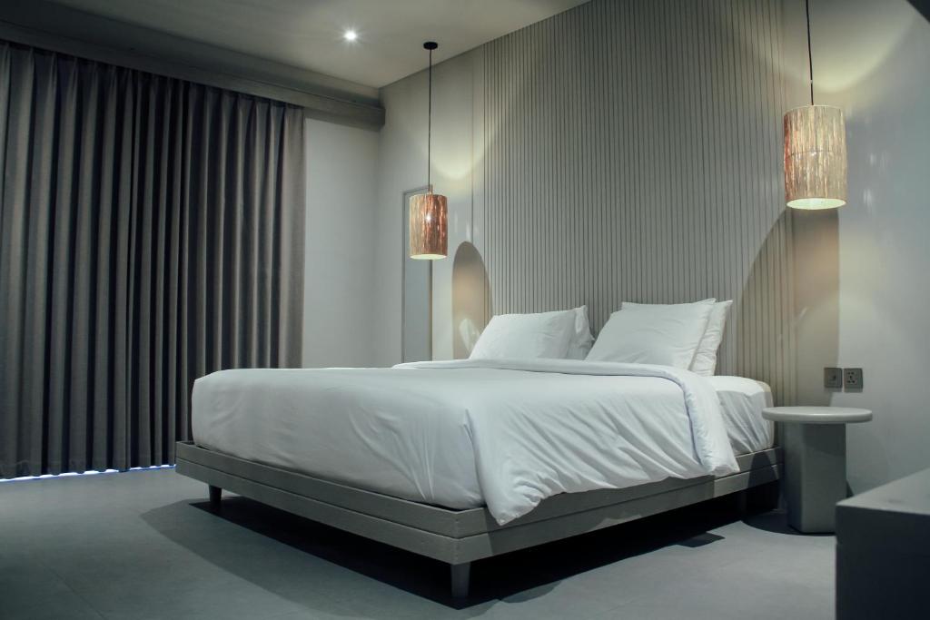 ein Schlafzimmer mit einem großen Bett mit weißen Laken und Kissen in der Unterkunft Greywood in Gili Trawangan