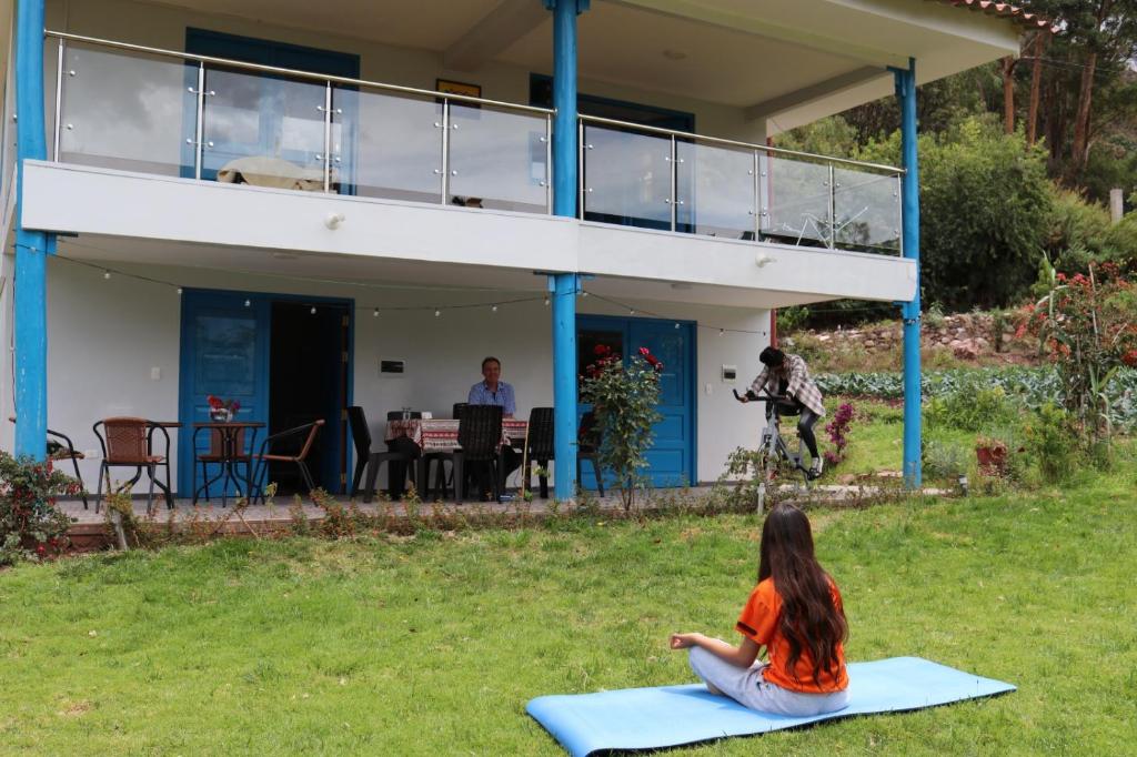 uma mulher sentada em um tapete de ioga em frente a uma casa em Soothing 2-bedroom country house in Huayllabamba em Huayllabamba