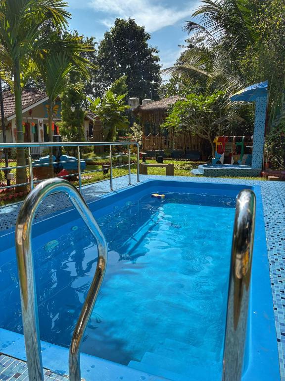a swimming pool with blue water and metal rails at Rimzim's Tatvamasi - A Pool Villa Retreat in Kudāl