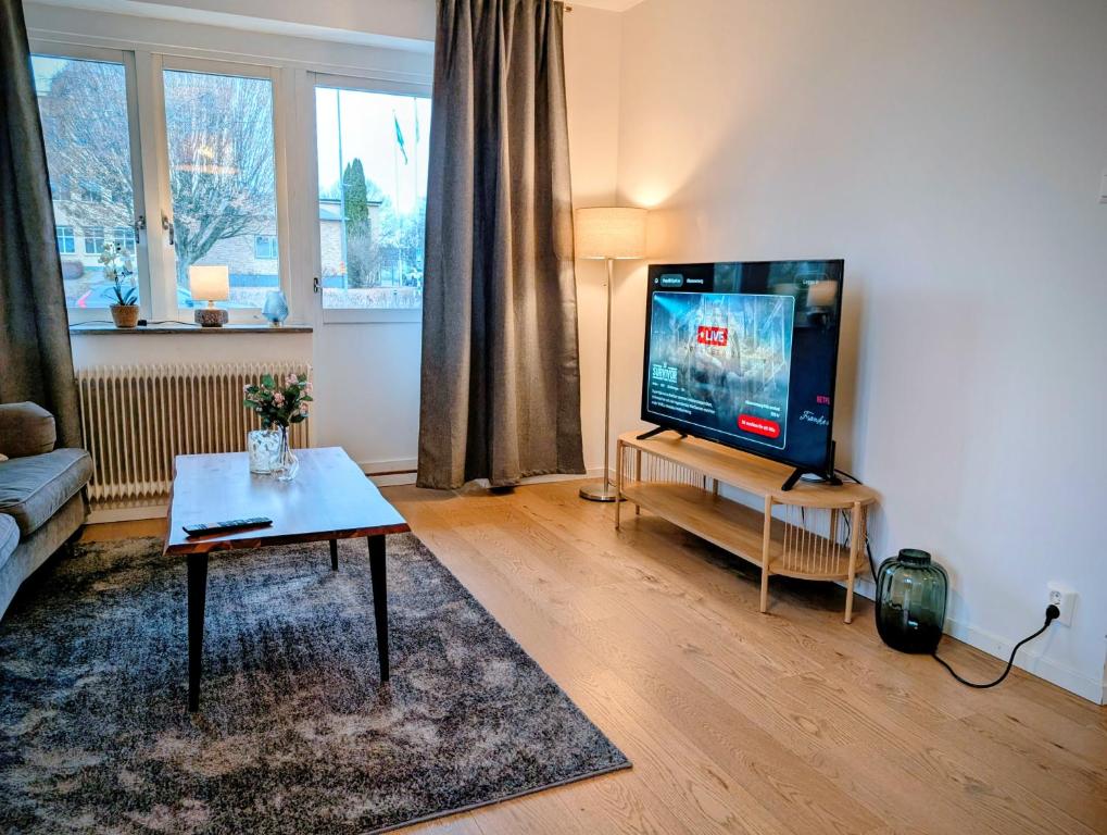 a living room with a flat screen tv and a table at Comfort Stay Apartments 1 in Katrineholm