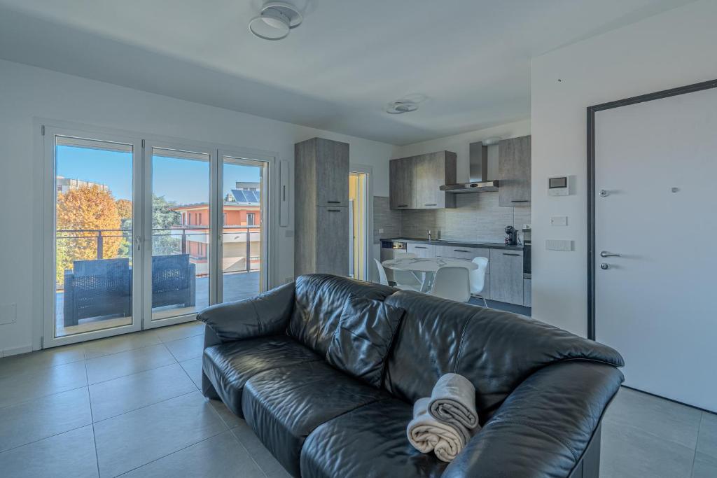 a living room with a leather couch and a kitchen at Casa Dalia in Garbagnate Milanese