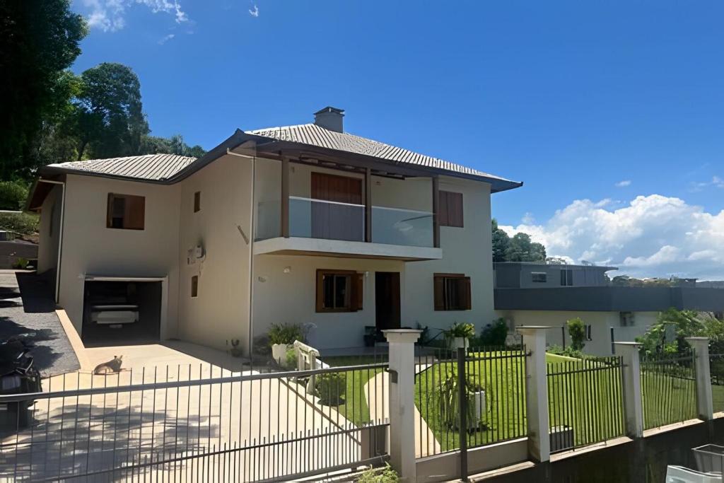 a white house with a fence in front of it at Casa vista das colinas in Gramado