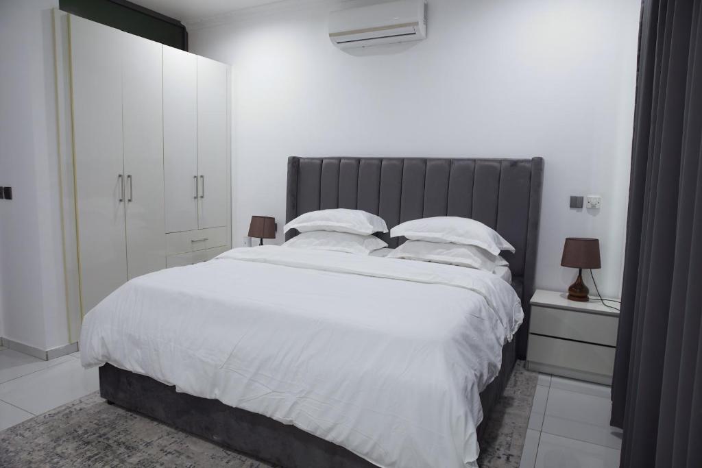 een slaapkamer met een groot bed met witte lakens en kussens bij Villa Alpaca in Accra