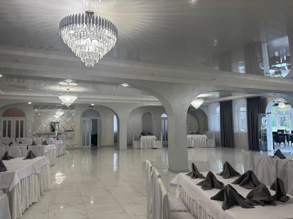 een feestzaal met witte tafels en stoelen en een kroonluchter bij Sn family in Radekhov