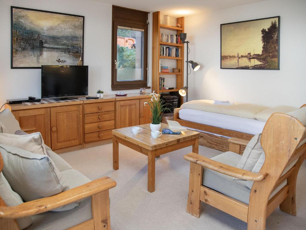 a living room with a bed and a tv at Apartment Primula Apt- B by Interhome in Wengen