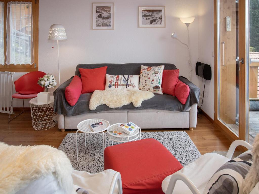 a living room with a couch and red pillows at Apartment Racer's Retreat Apt-12 by Interhome in Wengen