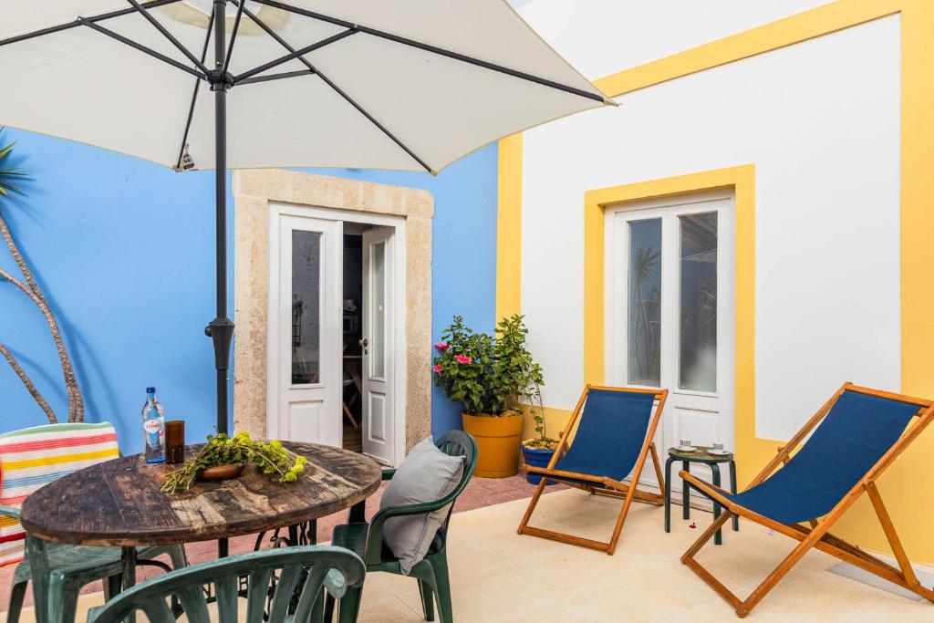 a patio with a table and chairs and an umbrella at NEW! Charming Palmela Retreat near Arrábida&Castle in Palmela