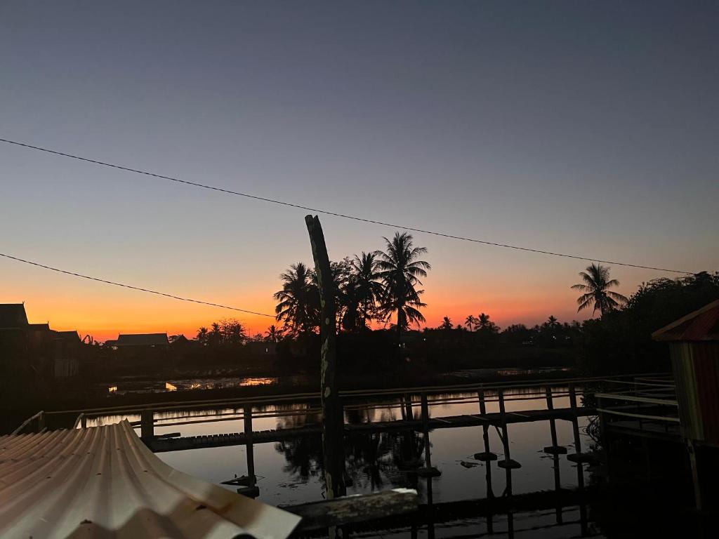 Sonnenuntergang über einem Fluss mit Brücke und Palmen in der Unterkunft Hill House Rammang-Rammang in Kasijala