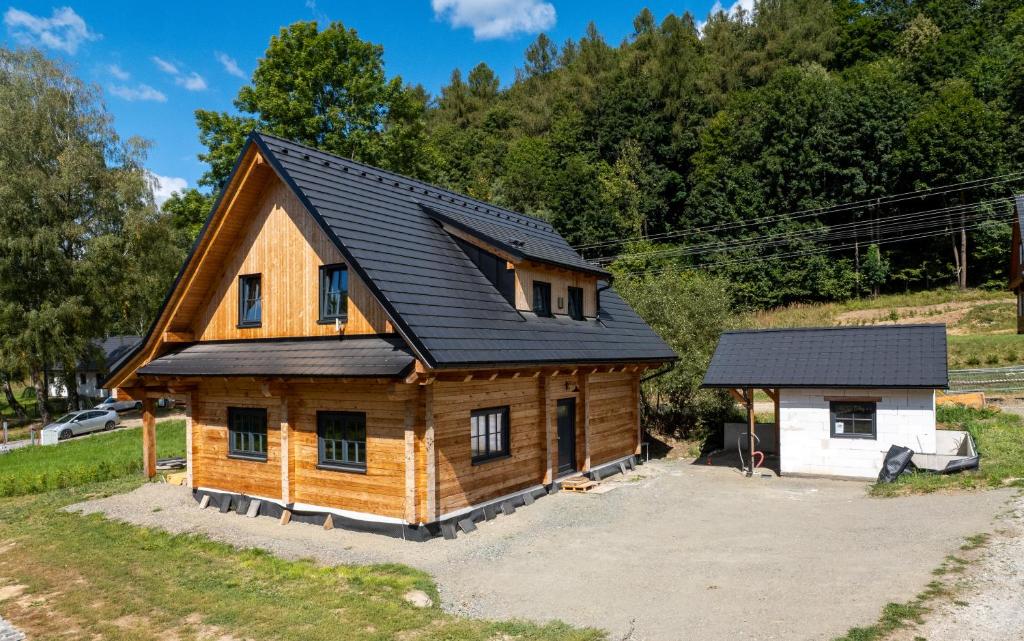 Cabaña de madera con techo negro y garaje en Chalupa Jesenka, en Sobotín