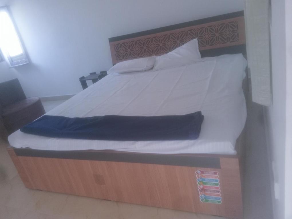 菩提伽耶Glamour palace的一张带木架、白色床单和枕头的床