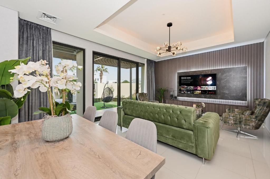 a living room with a green couch and a table at 3BR Luxurious Villa pool view DAMAC Hills 2 in Dubai