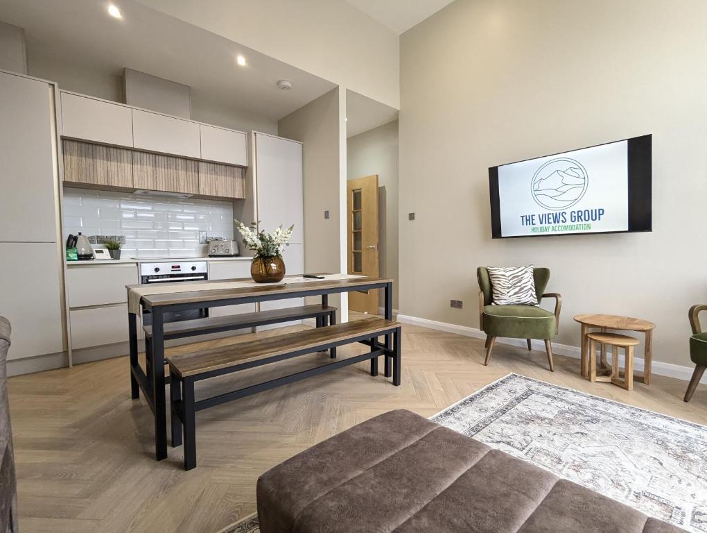 een woonkamer met een tafel en een tv aan de muur bij Waterfoot Penthouse Apartment in Newcastle
