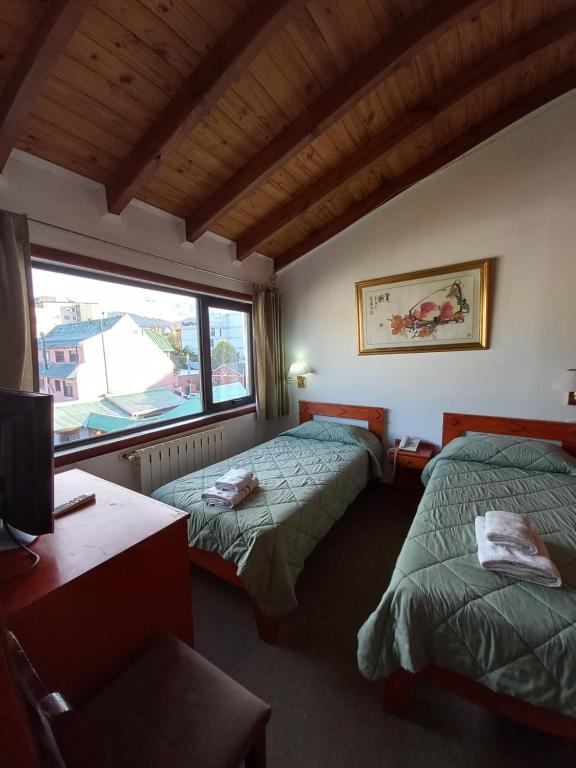 um quarto com duas camas, uma escrivaninha e uma janela em Hotel Antartida Argentina em Ushuaia