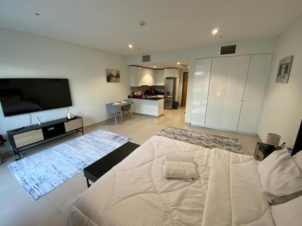 a bedroom with a large white bed and a flat screen tv at Nuchi studio in Dubai
