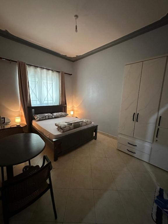 a bedroom with a bed and a table and a cabinet at Aurora two in Kampala