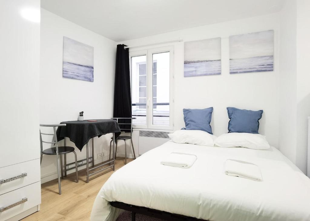 a white bedroom with a bed and a desk at Studio Near Metro & Marais & Hotel de Ville & Seine in Paris