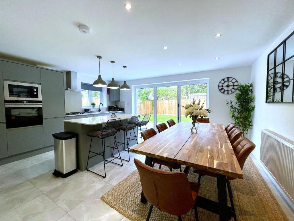グロスターにあるBrand NEW 4-bedroom detached house - 20-min walk to Gloucester Docks - Ample Parking - Superfast Wi-Fi - Long-stay rates!の木製のテーブルと椅子のあるキッチンとダイニングルーム