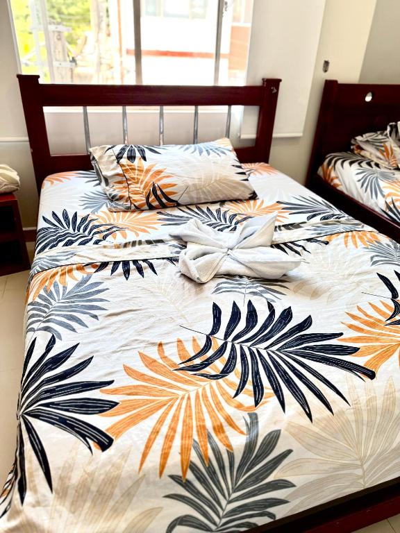 a bed with a colorful comforter with leaves on it at Hostal la 200 in Floridablanca