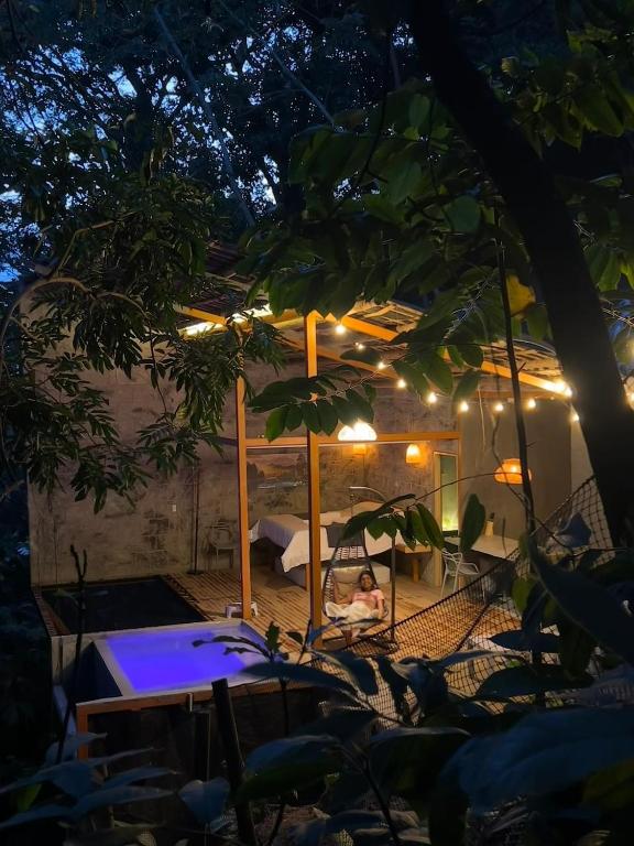 una donna seduta su un'amaca in un cortile di notte di Cabaña El Bosque Encanto Natural y Jacuzzi Privado a Sopetrán