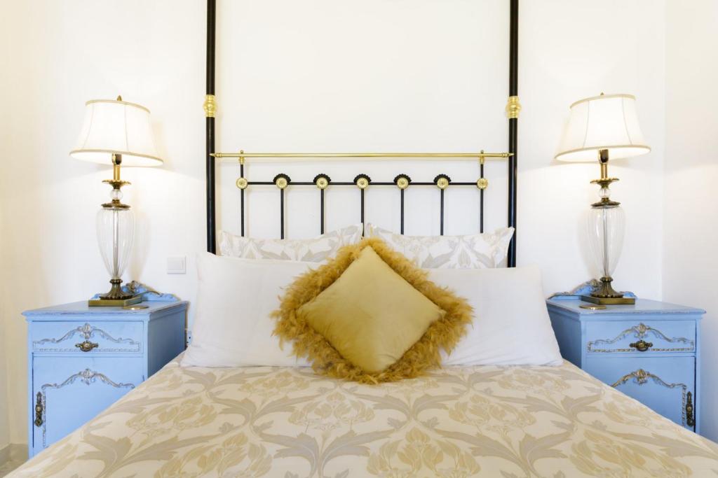 Valletta Townhouse Suite with a Maltese Balcony في إيل فورجانا: سرير مع طاولتين جانبيتين زرقاوين ومصباحين