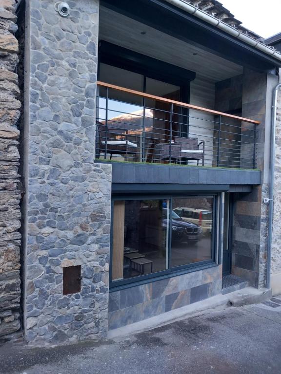 a stone building with a balcony and a patio at Maison de Lily in Cier-de-Luchon
