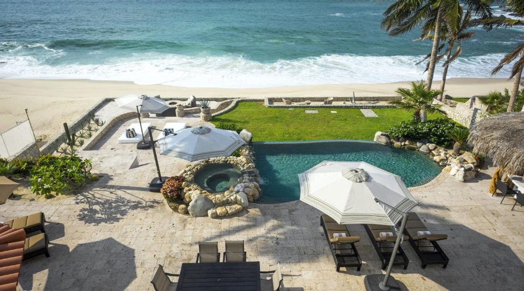 a swimming pool with umbrellas and chairs and the beach at Casa Edwards II in San José del Cabo