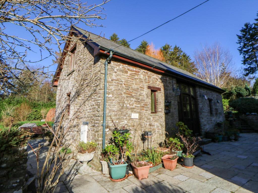 an old stone building with plants in pots at Maggie's Barn in Talgarth