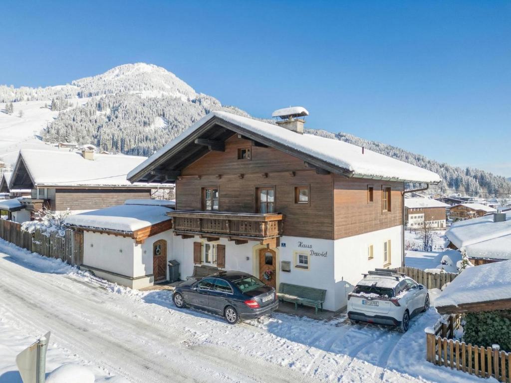 a house with two cars parked in the snow at Haus David in Kirchberg in Tirol