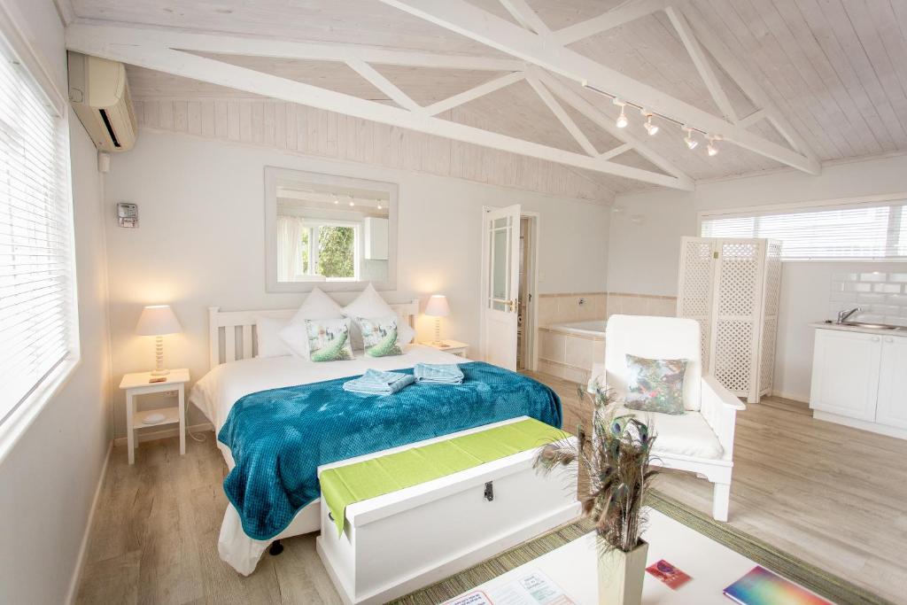 Un dormitorio blanco con una cama y una silla. en Slanting Acers - Unit B, en Wilderness