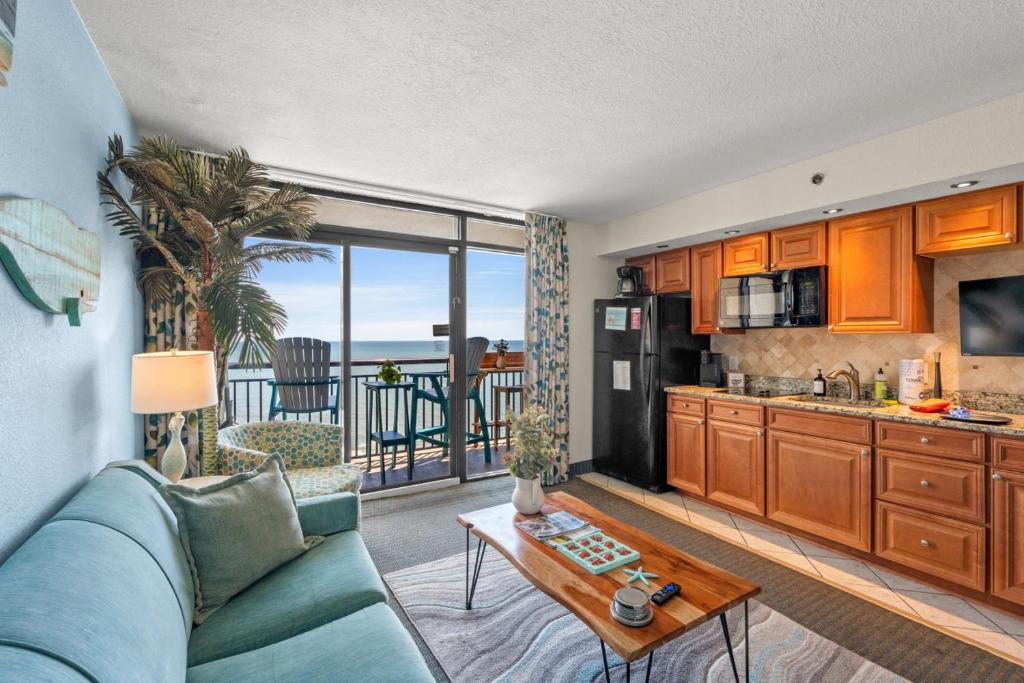 a living room with a blue couch and a kitchen at Beach Cove Resort - Oceanfront Condo - Unit 1516 in Myrtle Beach