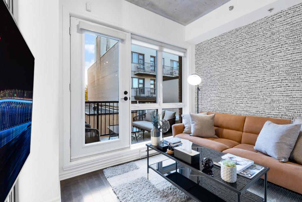 un soggiorno con un divano e una grande finestra di Pristine Parc Avenue Pad With Parking a Montréal