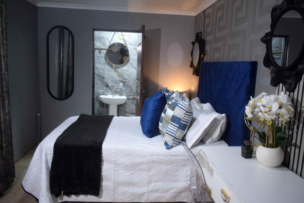 a bedroom with a bed with blue and white at Hlurile Lodge in Vosloorus