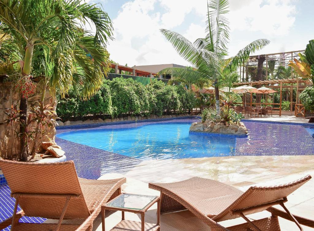 una piscina con dos sillas y palmeras en Pousada Sol e Mar, en Maragogi