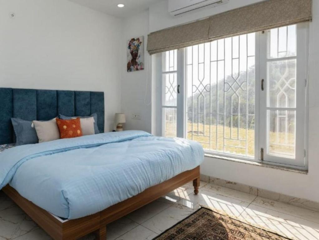 KandogalThe Chirping Sal Villa, by ShivStuti HomeStays的一间卧室配有一张带蓝色床头板的床和窗户。