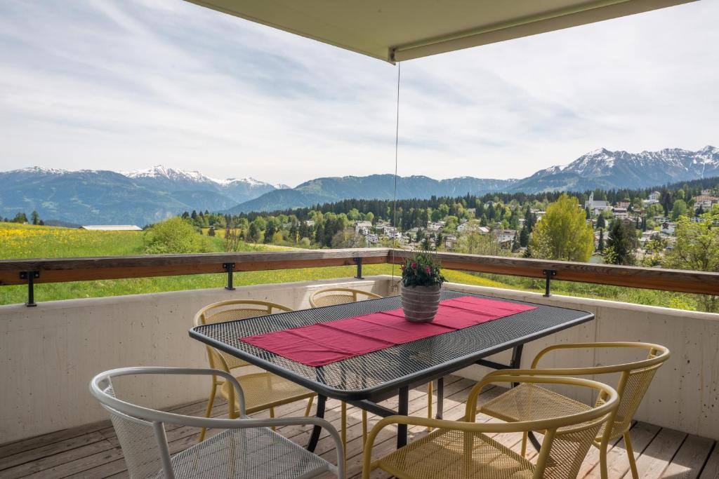 un tavolo e sedie su un balcone con vista sulle montagne di Edelweiss Lanezzi a Flims