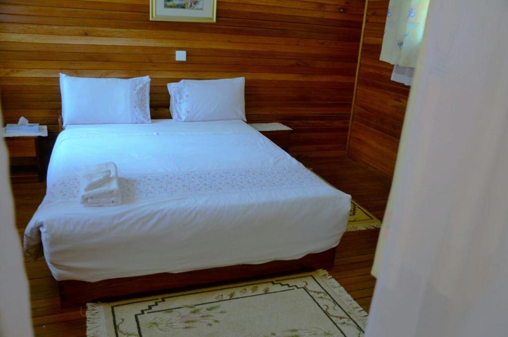 a bedroom with a large white bed with wooden walls at Bwigamiro Country Home Fort Portal in Fort Portal