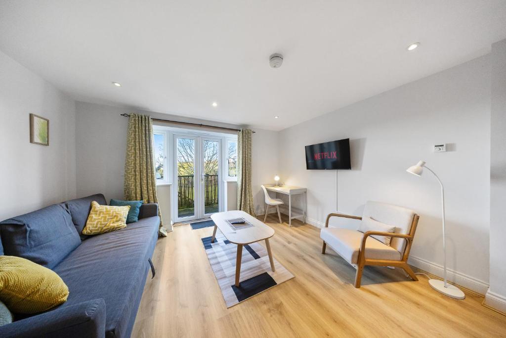a living room with a blue couch and a table at Modern Hastings Home for Groups with Garden Terrace and Dedicated Workspace in Hastings