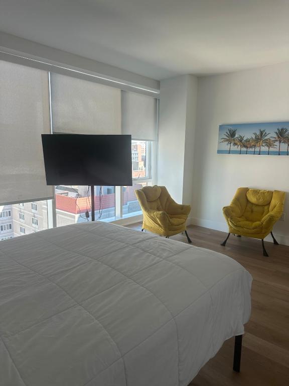 una camera da letto con un letto grande e due sedie di Bright, Modern Studio in White Plans a White Plains