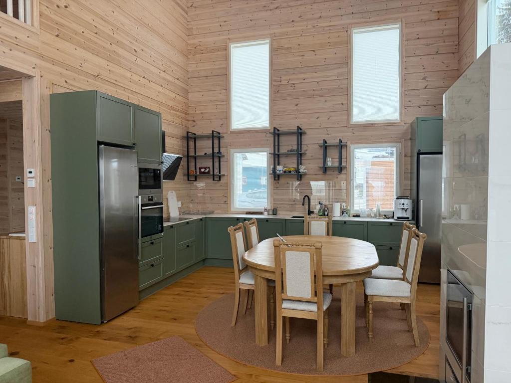 una cucina con mobili verdi, tavolo e sedie di Villa Siltasaari a Sotkamo