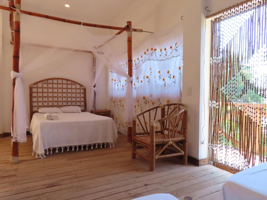 a bedroom with a bed and a chair and a window at Hostal Axlan in Puerto Escondido