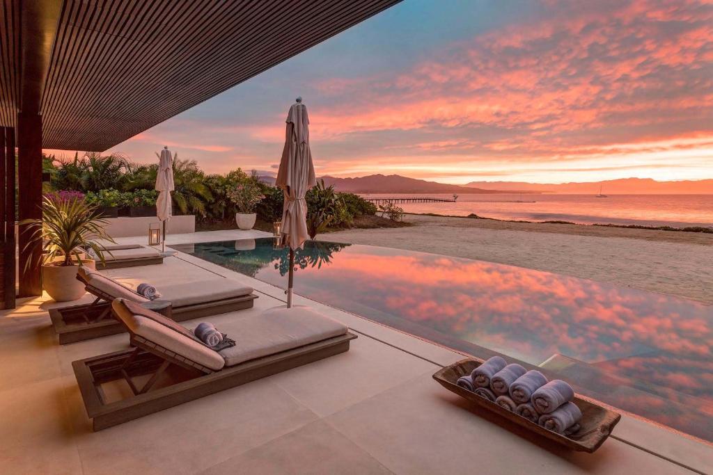 a villa with a infinity pool and a sunset at Beachfront Villa with Butler and Private Pool in Punta Mita
