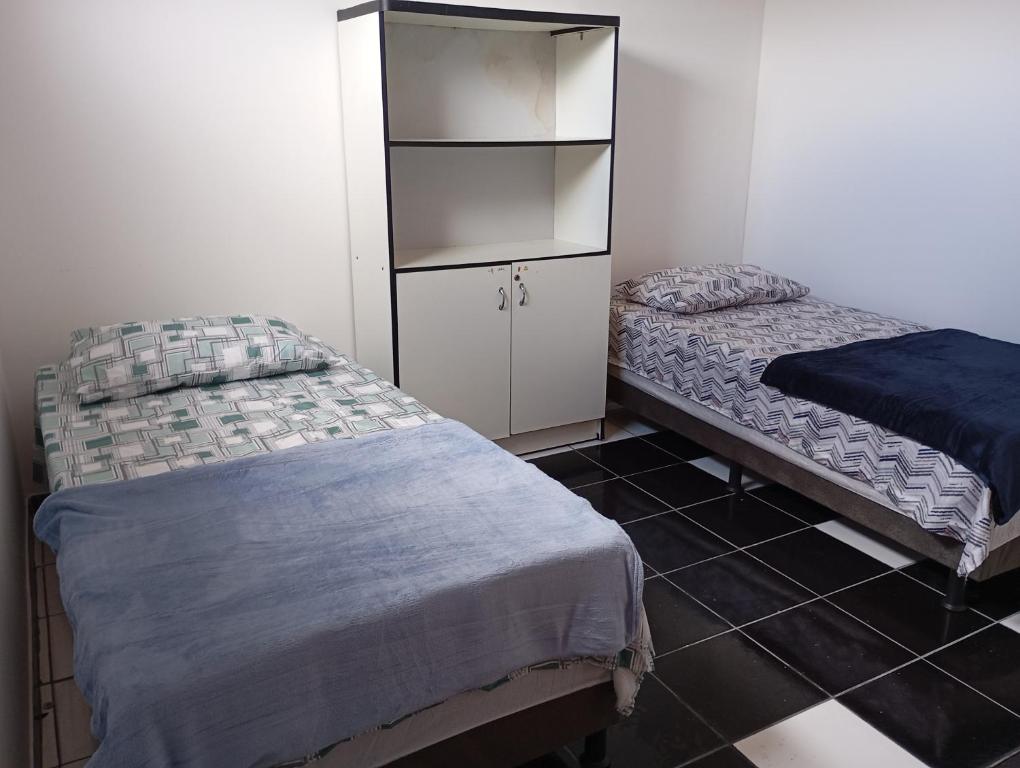 ein Schlafzimmer mit zwei Betten und einem Schrank in der Unterkunft Hospedagem próxima ao centro apto simples in Feira de Santana