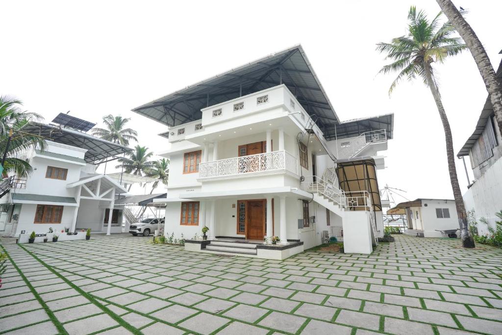 a house with a courtyard and palm trees at The Lawrences Aqua Stay in Cochin