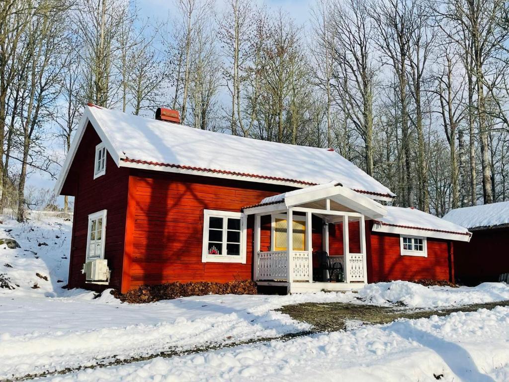 una piccola casa rossa con neve sul tetto di 5 person holiday home in ÅSEDA a Åseda
