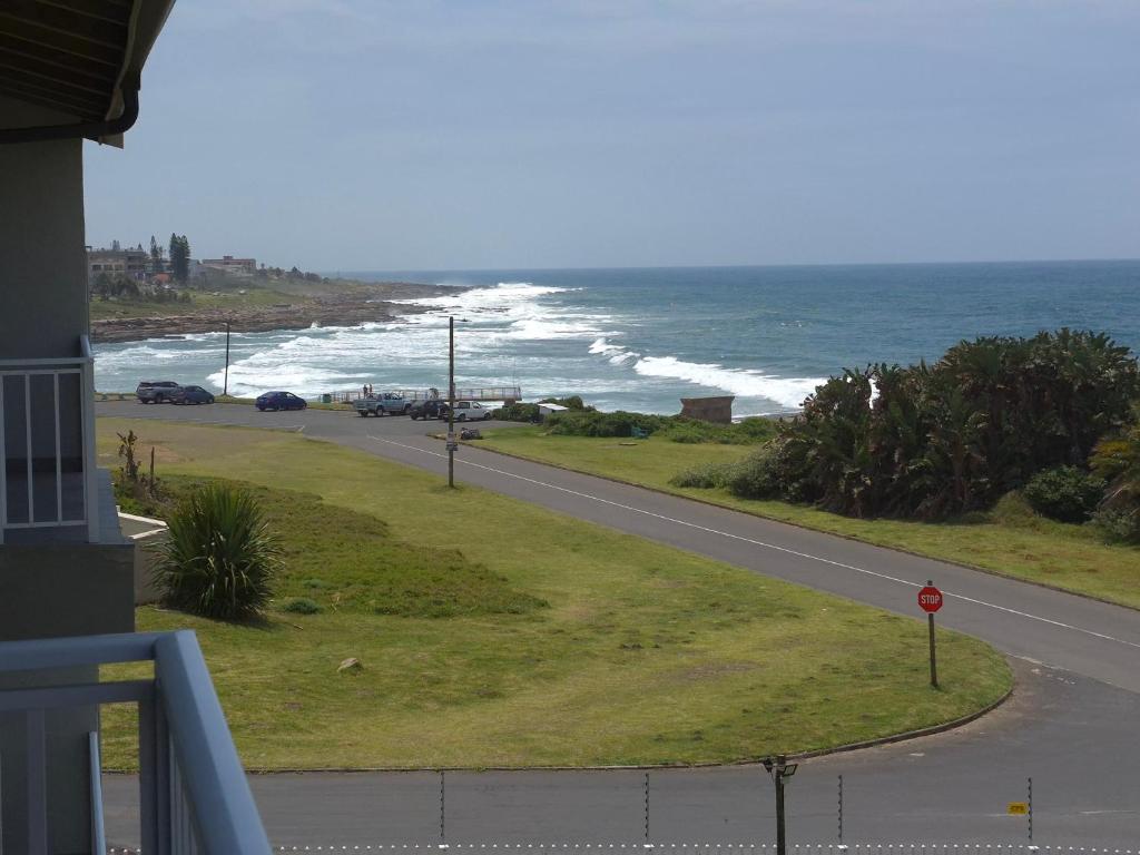 a road next to a beach with the ocean at Jakaranda Holiday Flat in Uvongo Beach