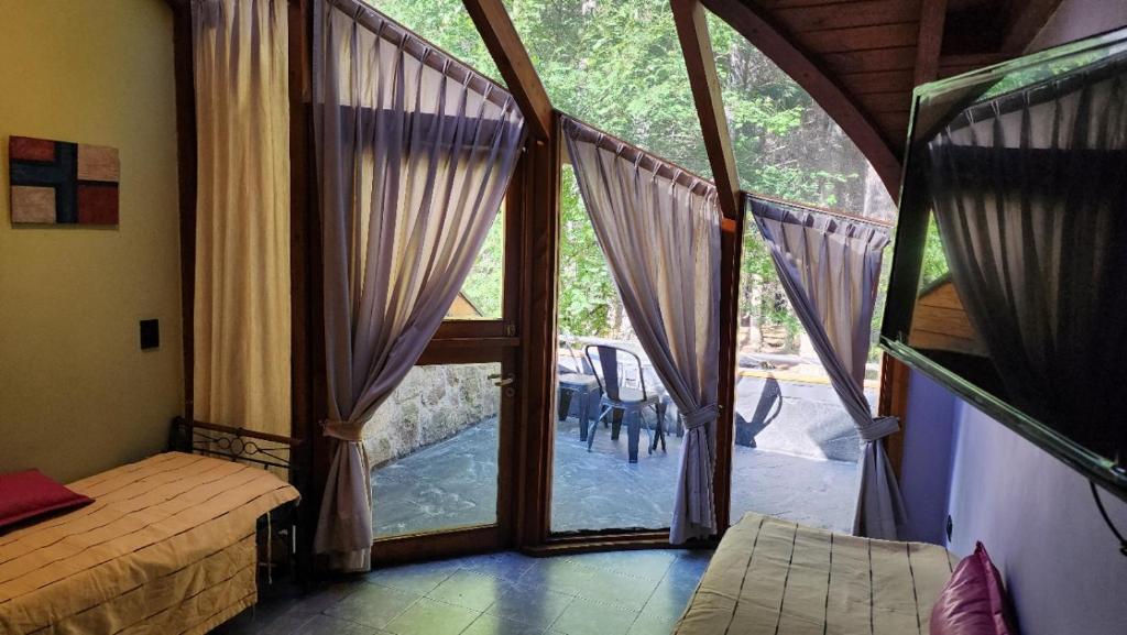 a bedroom with a large glass door to a patio at Casa Del Bosque Aparts in Villa La Angostura