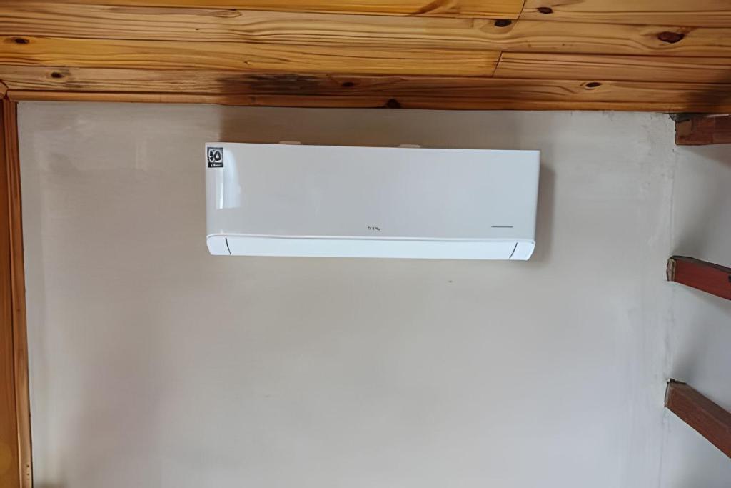 a white heater on a wall under a wooden ceiling at Recanto dos Canários - CHALÉ 1 in Visconde De Maua