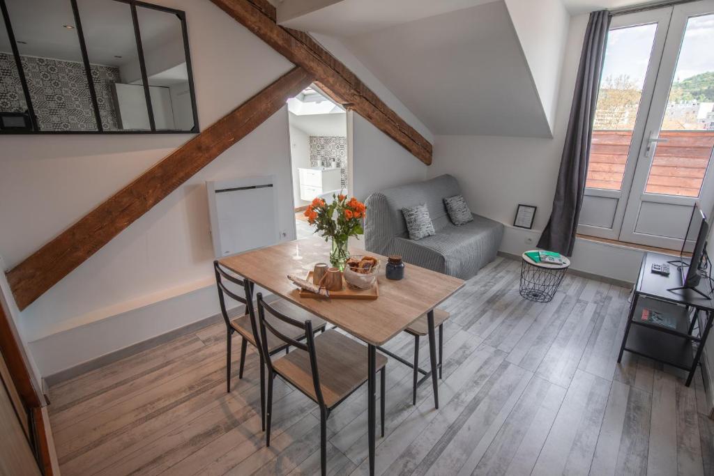 ein Wohnzimmer mit einem Tisch und einem Sofa in der Unterkunft Le Nid vue et détente à St Etienne in Saint-Étienne